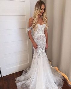 a woman in a white wedding dress standing on a wooden floor next to a door