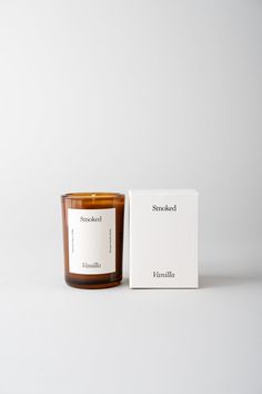 a candle sitting next to a box on a white surface with the label still attached