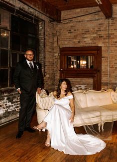 a bride and groom posing for a photo in an old - fashioned room with exposed brick walls