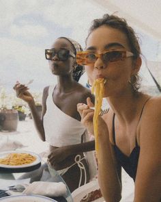 two women sitting at a table eating spaghetti