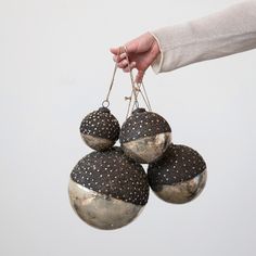 a hand is holding three ornaments in the shape of balls