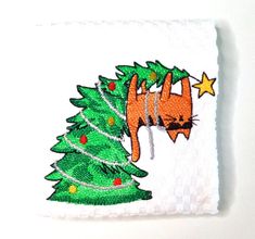 a white towel with a cat hanging from it's side next to a christmas tree