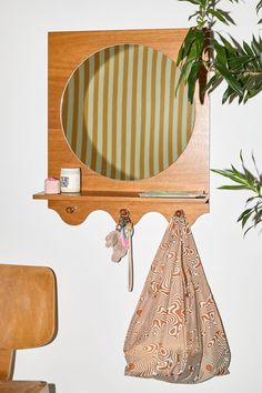 a mirror hanging on the wall next to a wooden chair and potted plant in front of it