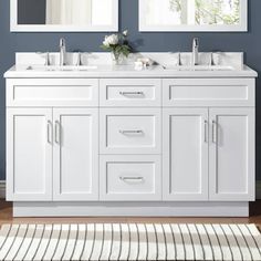 a bathroom vanity with two mirrors above it and a rug on the floor in front of it