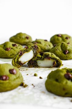 green cookies with white filling and chocolate chips on the top one cookie has been cut in half