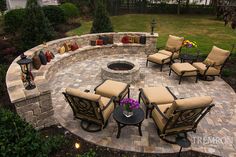 an outdoor fire pit surrounded by chairs and tables