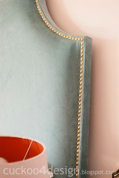 a blue upholstered headboard with gold beading on the top and bottom