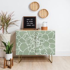 a blue and white cabinet sitting next to two potted plants on top of a hard wood floor