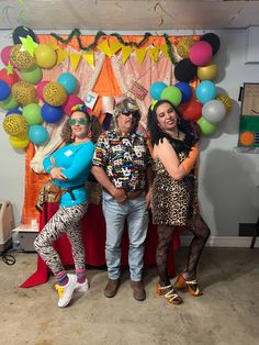 three people standing in front of a backdrop with balloons