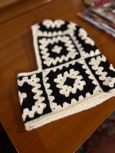 a crocheted black and white scarf sitting on top of a wooden table