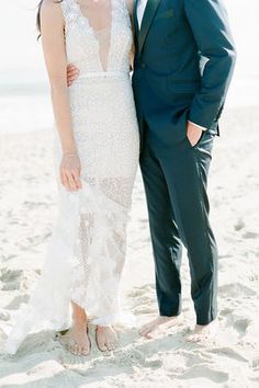 a bride and groom pose for a photo on the beach