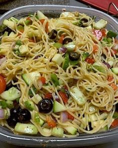 a bowl filled with pasta, olives and cucumbers on top of a table