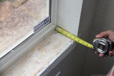 a person holding a measuring tape near a window