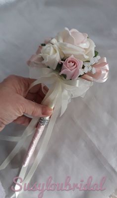 the brides bouquet is being held by her hand with a pink and white ribbon