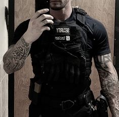 a man with tattoos taking a selfie in front of a mirror while holding a cell phone