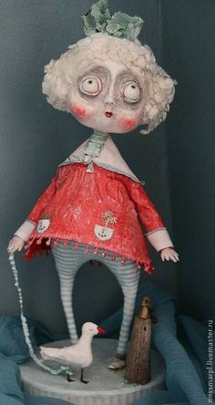 the doll is wearing a red dress and holding a white bird in her hand while standing on a pedestal