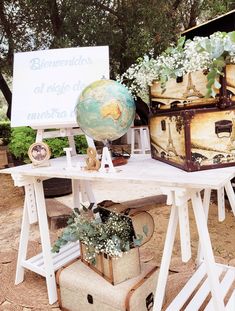 an old trunk is sitting on a table with flowers and other items around it, including a globe