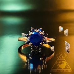 a blue ring sitting on top of a table next to some diamond studded rings