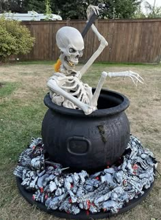 a skeleton sitting in a cauldster full of crushed up soda cans and bones