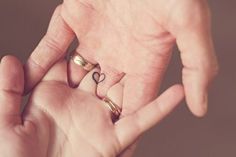 a person holding out their hand with two rings in the shape of a heart on it