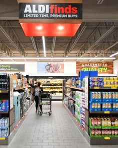 a person pushing a shopping cart through a grocery store filled with food and drinks on the shelves