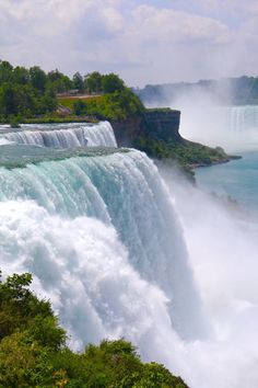 the waterfall is surrounded by lush green trees and blue water as it pours into the river