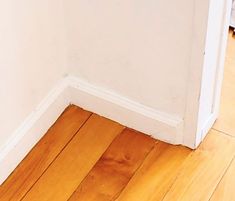 a cat is sitting on the floor in front of a door and looking at something