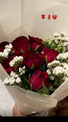 a bouquet of red and white flowers in someone's hand with the word i love you written on it