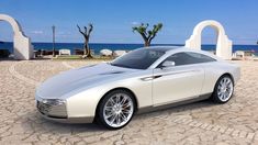 a white car parked on top of a cobblestone road next to the ocean