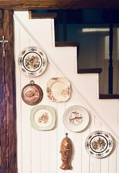 plates are hanging on the wall next to a stair case