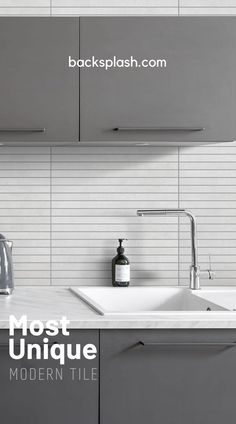 a white kitchen with gray cabinets and counter tops, an electric kettle on the sink