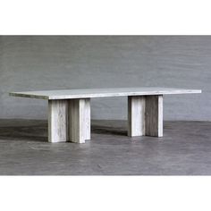 a white table sitting on top of a cement floor next to a gray wall in an empty room