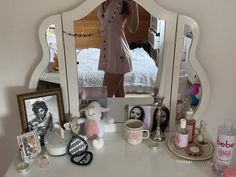 a white dresser topped with a mirror and lots of items