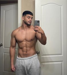 a shirtless man taking a selfie with his cell phone