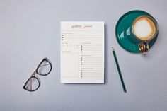 a cup of coffee next to a green plate and eyeglasses