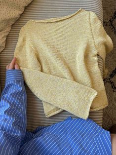 a person laying on top of a bed next to a yellow sweater and blue pants