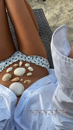 a woman laying on top of a beach next to shells