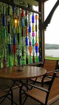 there is a table and two chairs under the glass bottles on the outside wall that are hanging from the ceiling