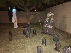 a cemetery with tombstones and ghost statues in the grass at night, next to a tree