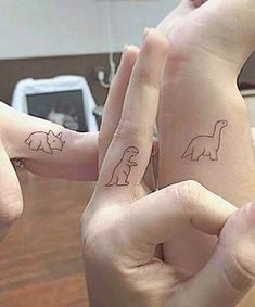 two people with matching tattoos on their fingers are making the shape of an elephant and rhinoceros