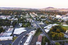 an aerial view of a city with lots of trees and mountains in the background,