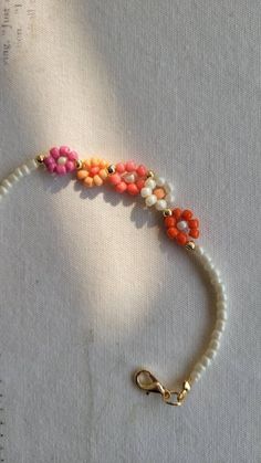 an orange, white and pink beaded bracelet with gold clasps on a table