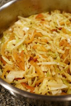 a metal bowl filled with coleslaw on top of a counter