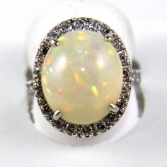 This Is A Fine Oval Fire Opal Solitaire Ring W/Diamond Halo. It Is Made Of 100% Natural 14kt White Gold And Is In Brand New Condition. It Has A Ctw Of 1.67ct (.72 Diamond/.95 Opal) And Weighs 5.4 Grams. The Fancy Diamonds Have A Clarity Of Si2 And G Color. This Beautiful Custom Piece Has An Excellent Oval Cut Fire Opal Stone, Surrounded By A Diamond Halo. This Ring Is The Latest In Fashion Design Having Unique Designer Qualities That Is Full Of Shine And Clarity. Formal White Diamond Gemstone Ring, Formal Fine Jewelry Opal Ring With Brilliant Cut, White Oval Diamond Ring With Vvs Clarity, Formal Opal Ring With Diamond Round Cut, White 14k Gold Jewelry With Brilliant Cut, Formal Opal Ring With Diamond Prong Setting, Gia Certified White Diamond Ring In Sterling Silver, White Diamond Platinum Ring, Formal White Gold Opal Ring With Brilliant Cut