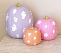 three painted pumpkins sitting on top of a shelf