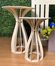 two wooden side tables sitting next to each other on a wood floor with flowers in the background