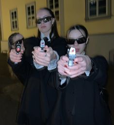 three women dressed in black holding up their cell phones and pointing them at the camera