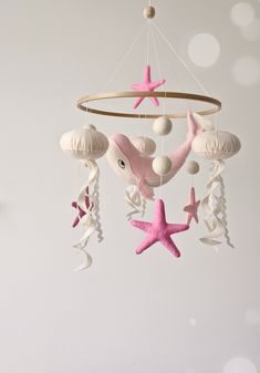 a pink and white starfish mobile hanging from the ceiling with shells, sea stars and seashells