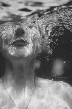 a black and white photo of a woman under water