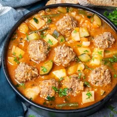 meatball soup in a black bowl with bread on the side